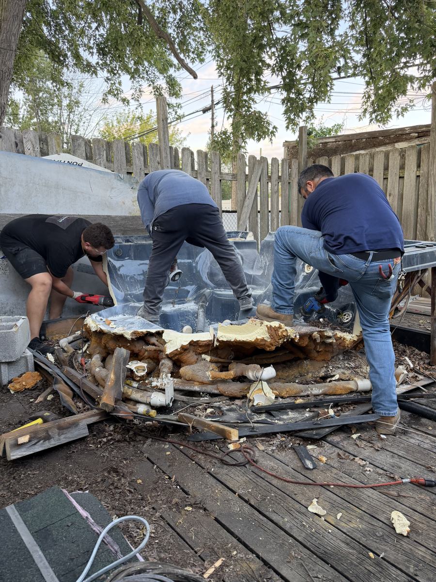 Crew cutting apart a hot tub on a deck in Taylor, MI